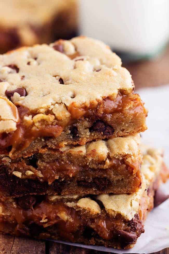 Perfectly chewy chocolate chip cookie bars with an ooey gooey peanut butter caramel center. These will be one of the best treats that you make! Stack of peanut butter caramel chocolate chip cookie bars.