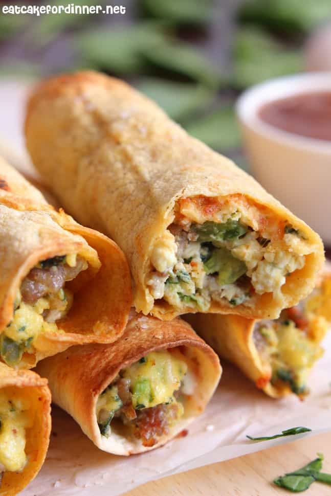 A baked taquito that is crispy on the outside and loaded with flavorful breakfast ingredients on the inside. Sausage, Spinach and Egg Breakfast Taquitos stacked.