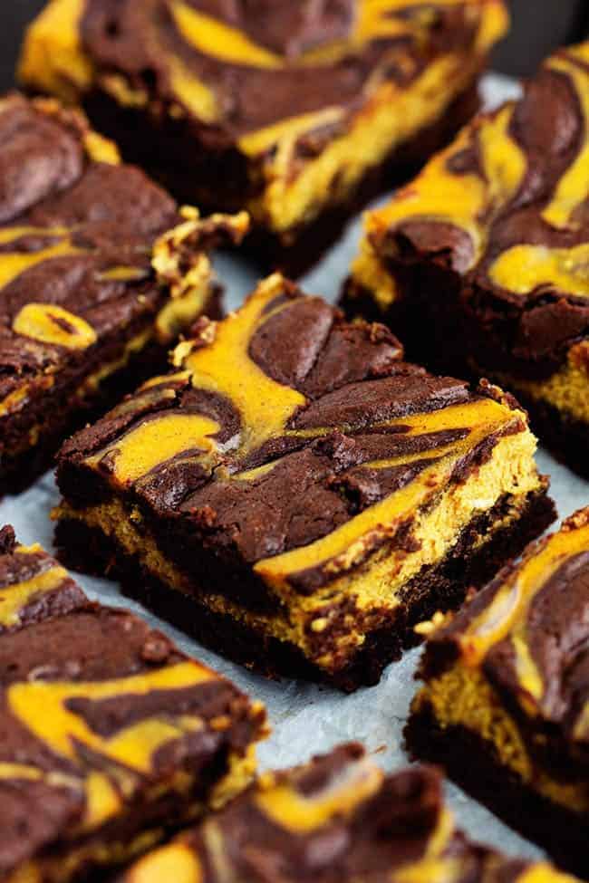 Perfectly moist and fudgy brownies swirled with pumpkin cheesecake. These are so rich and delicious and they make an amazing fall treat! pumpkin cheesecake brownies cut on a tray.