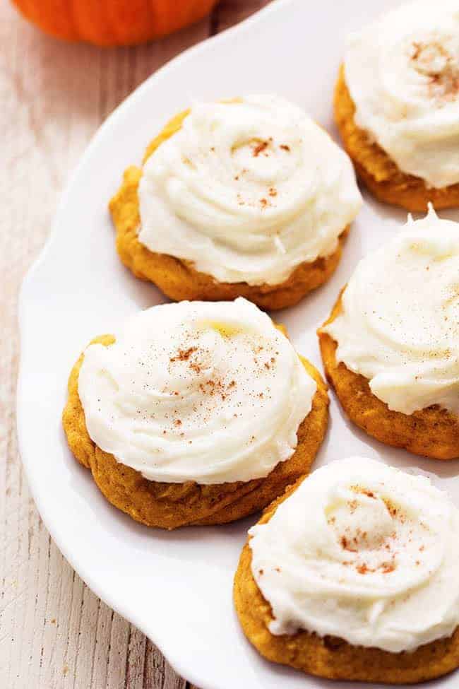Delicious and soft pumpkin cookies that just melt in your mouth! These are the BEST pumpkin cookies and the cream cheese frosting on top is fantastic! pumpkin cookies on a white plate.