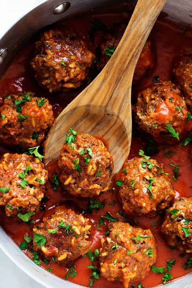 Porcupine Meatballs are juicy, well-seasoned meatballs with tender rice simmered in a rich, tangy tomato sauce. This recipe comes straight from my grandma’s kitchen, and trust me, your family’s about to be obsessed! Porcupine Meatballs in a skillet cooking with a wooden spoon picking up a meatball.