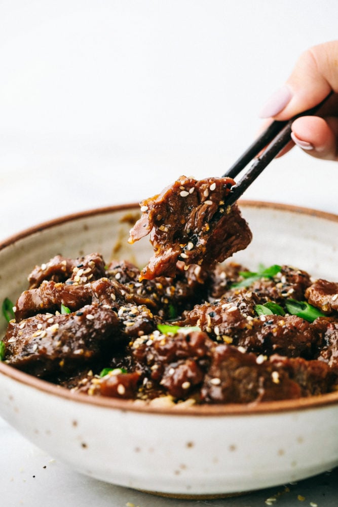 Amazing and flavorful beef that slow cooks to tender melt in your mouth perfection! This will be one of the best meals that you will make! Korean beef in a bowl with black chopsticks.