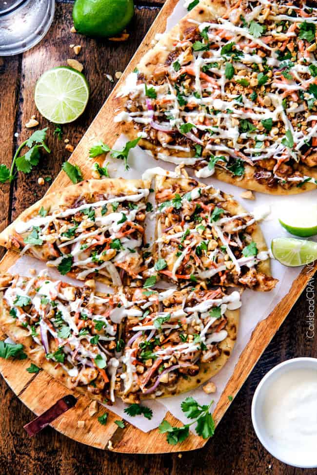Thai Chicken Flatbread Pizza smothered in easy tangy peanut sauce, tender chicken, ย carrots, sprouts, mozzarella cheese and the option of Coconut Crema drizzle - an amazing flavor bursting quick dinner the whole family will love! Thai Chicken Flatbread Pizza areal view on a wooden board.