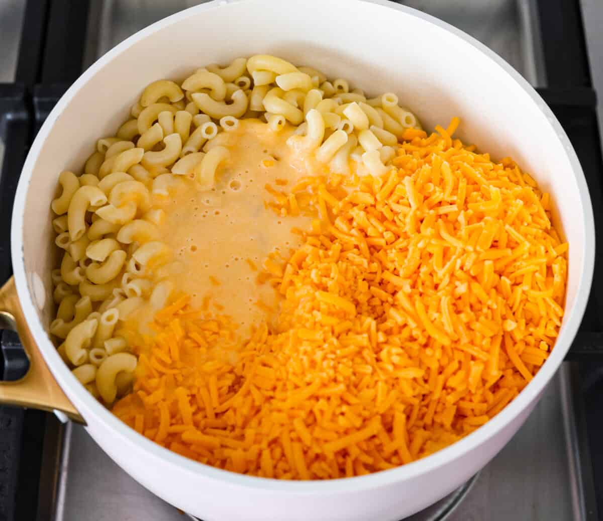 This cheesy butternut squash pasta recipe is loaded with cozy fall squash and ooey, gooey cheese,ย making it a perfect meal to warm up to on crisp fall evenings. Even better, it can be ready in less than an hour! Overhead shot of cooked pasta, squash puree and cheese in a pot on the stovetop.