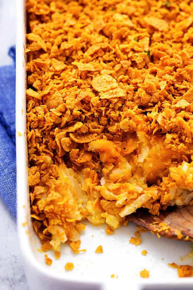 A cheesy potato casserole full of melted cheese, sour cream, onions, and garlic with a crunchy top. This is full of amazing flavor and will be the star of the dinner table! funeral potatoes in a white baking dish.