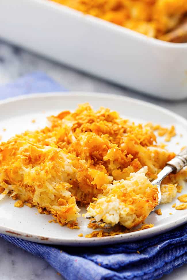 A cheesy potato casserole full of melted cheese, sour cream, onions, and garlic with a crunchy top. This is full of amazing flavor and will be the star of the dinner table! funeral potatoes on a white plate.