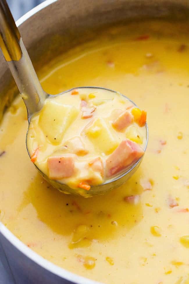 This hearty and delicious soup is full of ham, potatoes, and veggies. The real cheddar cheese inside adds such amazing flavor to this comforting soup! It became an instant favorite at our house! Ham and Cheddar Potato Soup being scooped up in a ladle.