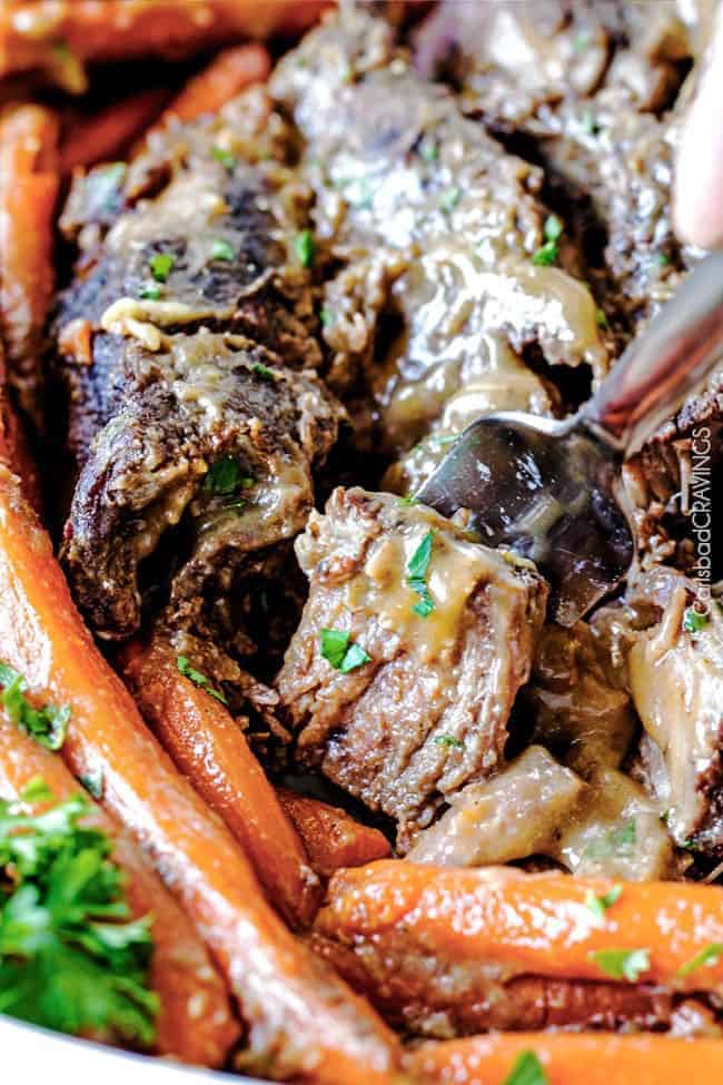 Fall apart juicy, tender roast with hardly any hands-on prep time is easy enough for everyday, delicious enough for company! Pot roast close up with carrots and a fork pulling a bite of meat off.