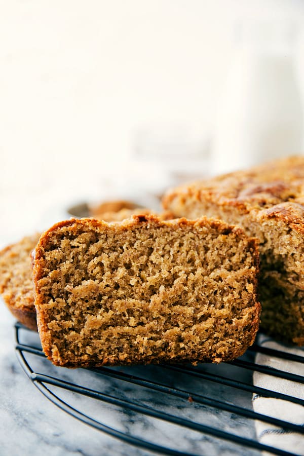 A healthier banana cake made in ONE bowl and covered in a dark chocolate frosting. The perfect way to use up those over ripe bananas! Banana cake slice on a cooling rack.