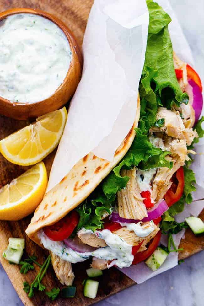 Easy to make chicken gyros that only take minutes to throw into the slow cooker! They are light and delicious and packed with amazing greek flavor! Slow Cooker Greek Chicken Gyros with Tzatziki seasoned chicken, tender vegetables and a classic cool cucumber sauce wrapped in a flat bread