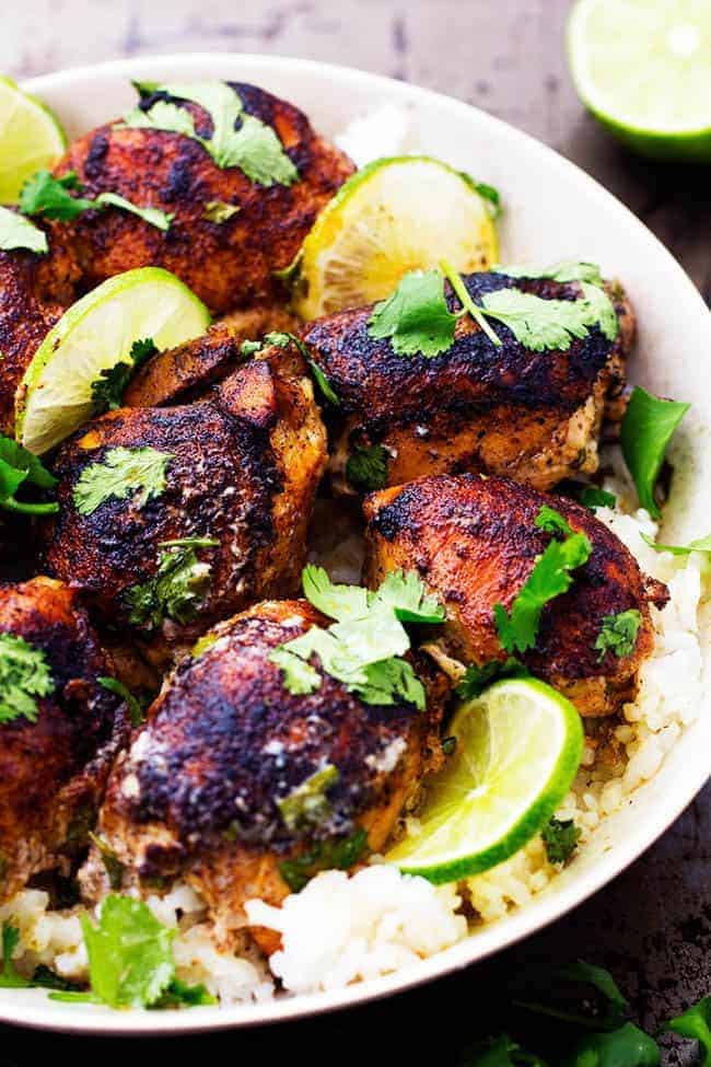 Tender and juicy seasoned and pan seared chicken thighs slow cook with a flavorful and light cilantro lime sauce. ย This meal is packed with flavor and absolutely delicious!ย Slow Cooker Creamy Cilantro Lime Chicken over rice in a white bowl.