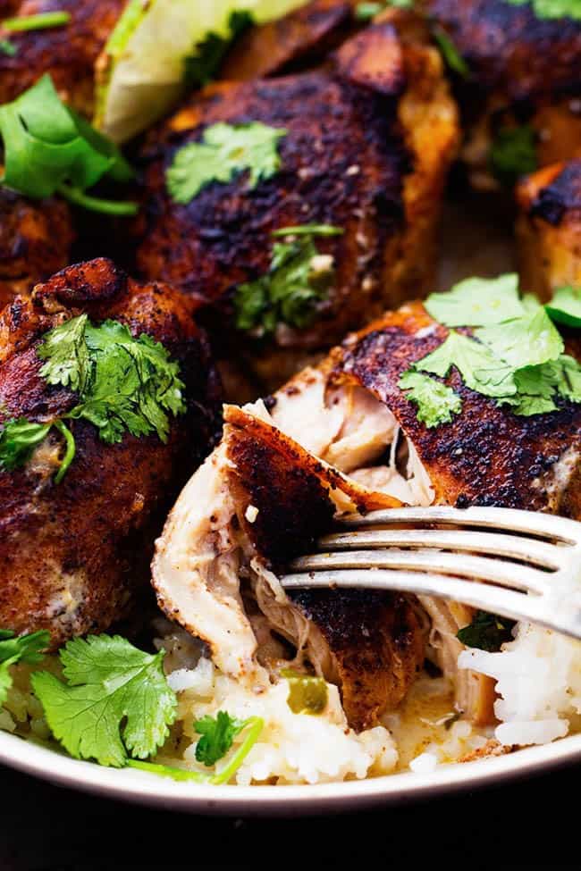 Tender and juicy seasoned and pan seared chicken thighs slow cook with a flavorful and light cilantro lime sauce. ย This meal is packed with flavor and absolutely delicious!ย Slow Cooker Creamy Cilantro Lime Chicken over rice in a white bowl.