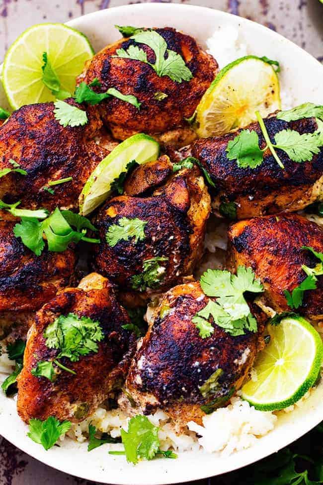Tender and juicy seasoned and pan seared chicken thighs slow cook with a flavorful and light cilantro lime sauce. ย This meal is packed with flavor and absolutely delicious!ย Slow Cooker Creamy Cilantro Lime Chicken over rice in white bowl.