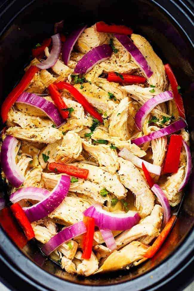 Easy to make chicken gyros that only take minutes to throw into the slow cooker! They are light and delicious and packed with amazing greek flavor! Chicken in a slow cooker with peppers and onions.