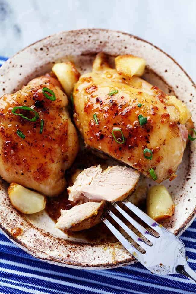 A quick and easy 30 minute meal that is packed with amazing honey dijon garlic flavor! The chicken is so juicy and tender and the sauce is sweet and tangy... you are going to love it! Chicken on plate with garlic and onion.
