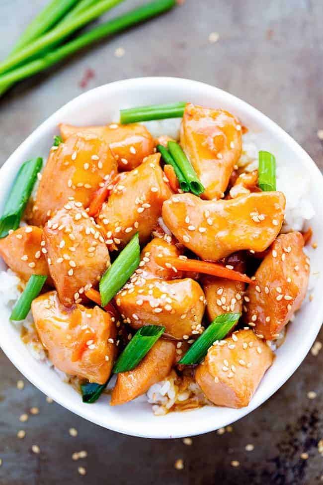This Slow Cooker Mongolian Chicken takes just five minutes to throw into the slow cooker and the flavor is out of this world! Tender and juicy slow cooked chicken in a lightened up mongolian sauce that is sure to wow your family! Mongolian chicken over white rice in a white bowl.