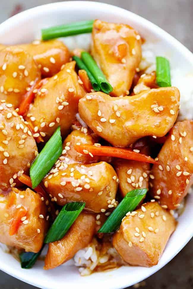 This Slow Cooker Mongolian Chicken takes just five minutes to throw into the slow cooker and the flavor is out of this world! Tender and juicy slow cooked chicken in a lightened up mongolian sauce that is sure to wow your family! Mongolian chicken over white rice in a white bowl.