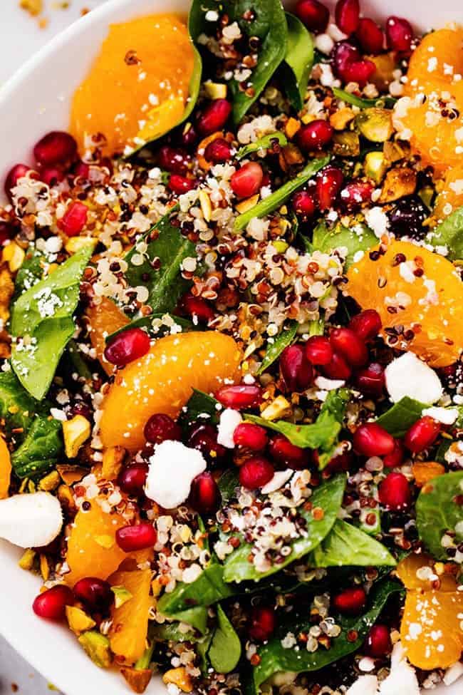 A mouthwatering winter salad with quinoa, spinach, mandarine oranges, and crunchy pistachios. Topped with a creamy lemon greek yogurt dressing and feta cheese this makes one unforgettable salad! CLOSE UP OF WINTER POMEGRANATE ORANGE QUINOA SALAD WITH CREAMY LEMON GREEK YOGURT DRESSING.
