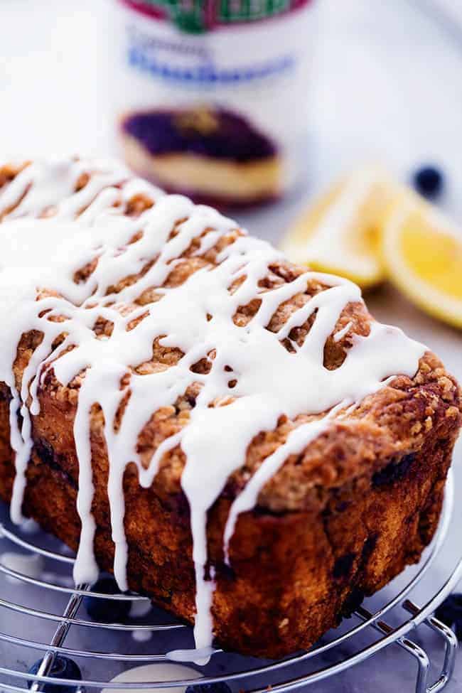 An amazingly moist muffin bread filled with blueberry pie filling. Topped with a crumb topping and drizzled in a lemon glaze this bread is incredible!ย Blueberry pie bread on a cooling rack with fresh lemon glaze.
