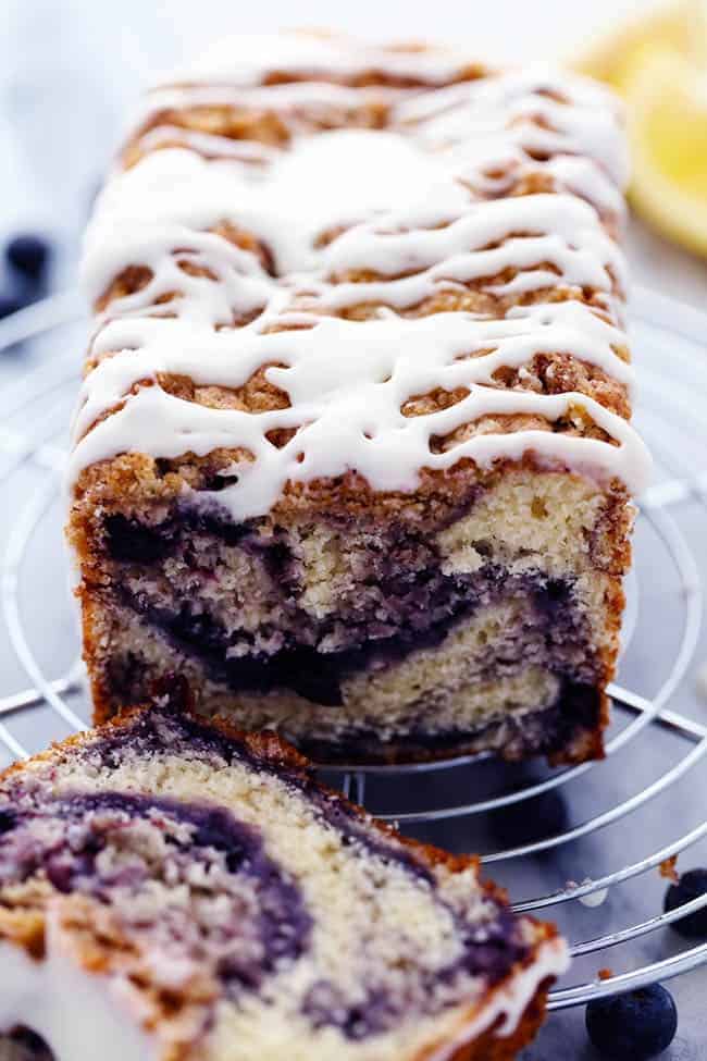 An amazingly moist muffin bread filled with blueberry pie filling. Topped with a crumb topping and drizzled in a lemon glaze this bread is incredible!ย Blueberry pie bread with the lemon glaze on a cooling rack.
