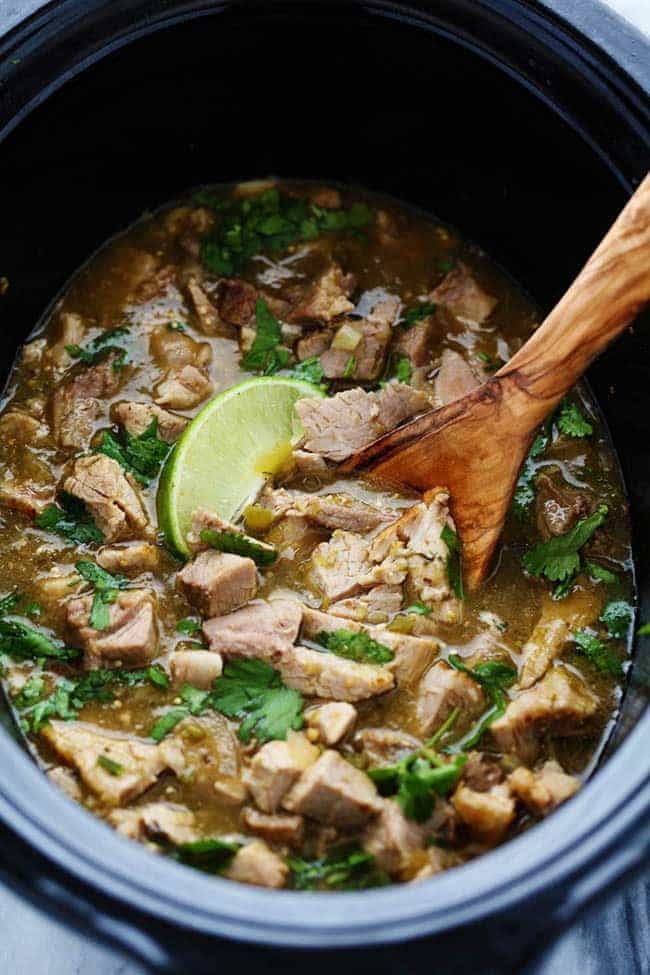 This is easily the BEST chili verde that I have EVER had! The pork is tender and full of amazing flavor and is made right in the slow cooker! Slow cooker pork Chile Verde with a wooden spoon.