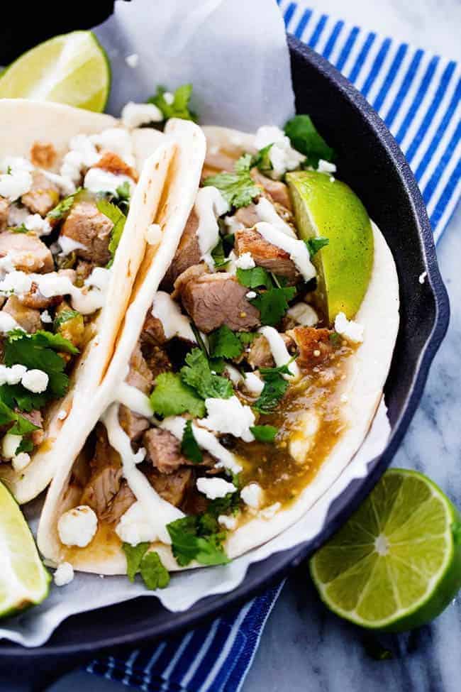 This is easily the BEST chili verde that I have EVER had! The pork is tender and full of amazing flavor and is made right in the slow cooker! Slow Cooker Pork Chili Verde in pita tacos in a black plate with fresh limes on the side.