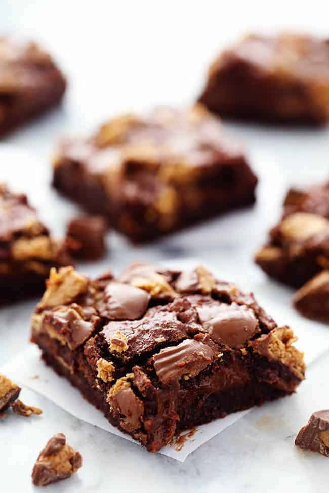 Ultra rich brownies with a creamy hot fudge cheesecake centerย and topped with peanut butter cups. So many delicious things in one amazing brownie that your family will go crazy for! Close up photo of Hot Fudge Peanut Butter Cup Cheesecake Brownies.