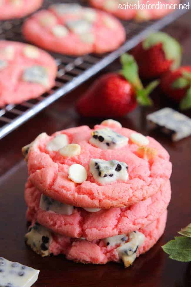 Easy and delicious cookies that are made with a cake mix and pudding mix with delicious cookies and cream pieces hidden inside! They are a fun pink color with a crisp edge and chewy center! Strawberry Cookies 'n Cream Cookies with whole fresh strawberries in background