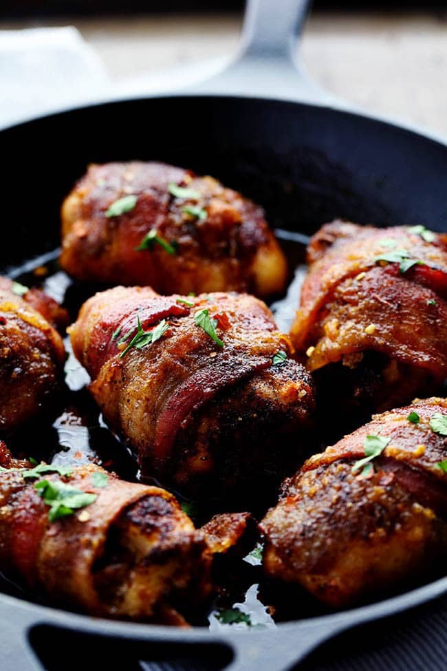 Tender and Juicy Chicken that is wrapped in bacon and coated in a blend of spices. It bakes in brown sugar which caramelizes when it cooks. You are going to love the sweet and spicy flavor! Close up photo sweet and spicy bacon wrapped chicken in a skillet.