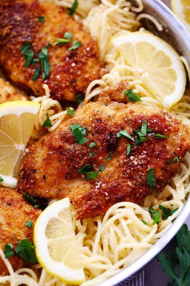 Crispy, tender and juicy parmesan crusted chicken over the most incredible creamy lemon garlic pasta! This is a must make meal! Close up photo of Crispy Parmesan Chicken with Creamy Lemon Garlic Pasta in a metal frying pan.