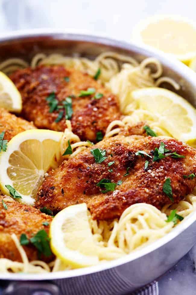 Crispy, tender and juicy parmesan crusted chicken over the most incredible creamy lemon garlic pasta! This is a must make meal! Crispy Parmesan Chicken with Creamy Lemon Garlic Pasta in a metal frying pan.