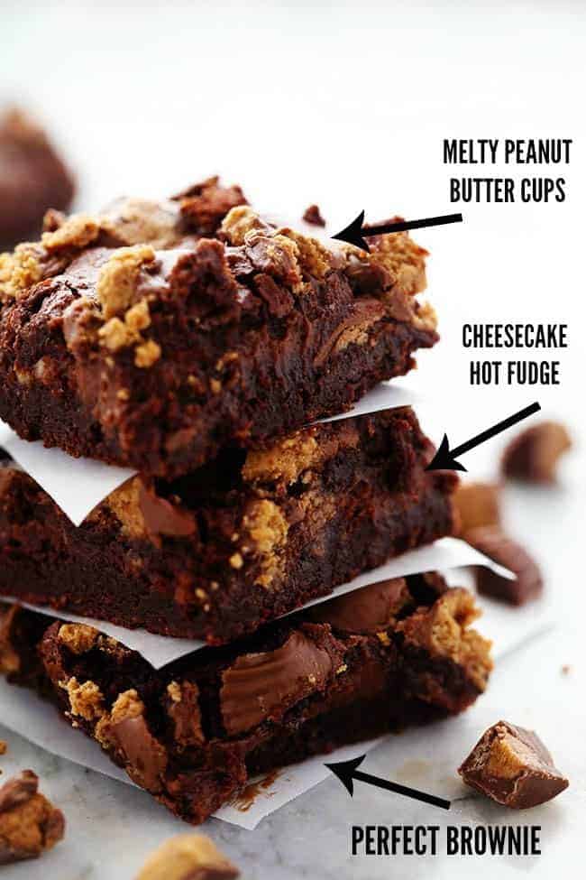 Ultra rich brownies with a creamy hot fudge cheesecake centerย and topped with peanut butter cups. So many delicious things in one amazing brownie that your family will go crazy for! Hot Fudge Peanut Butter Cup Cheesecake Brownies stacked on top of one another with parchment paper in between them and descriptions of the different layers of the brownie.