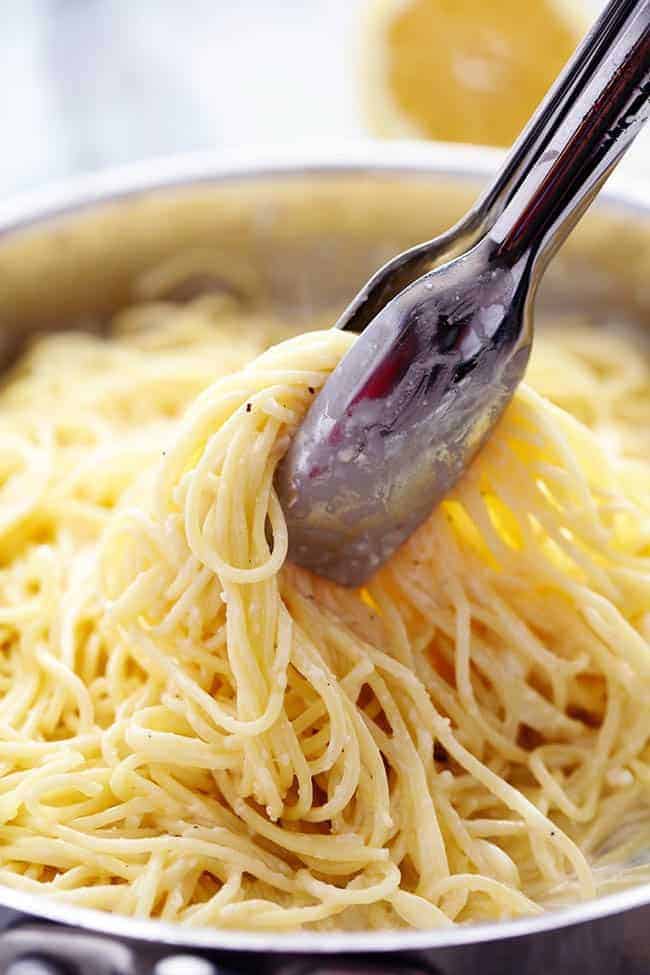 Crispy, tender and juicy parmesan crusted chicken over the most incredible creamy lemon garlic pasta! This is a must make meal! Creamy Lemon Garlic Pasta with a set of tongs.