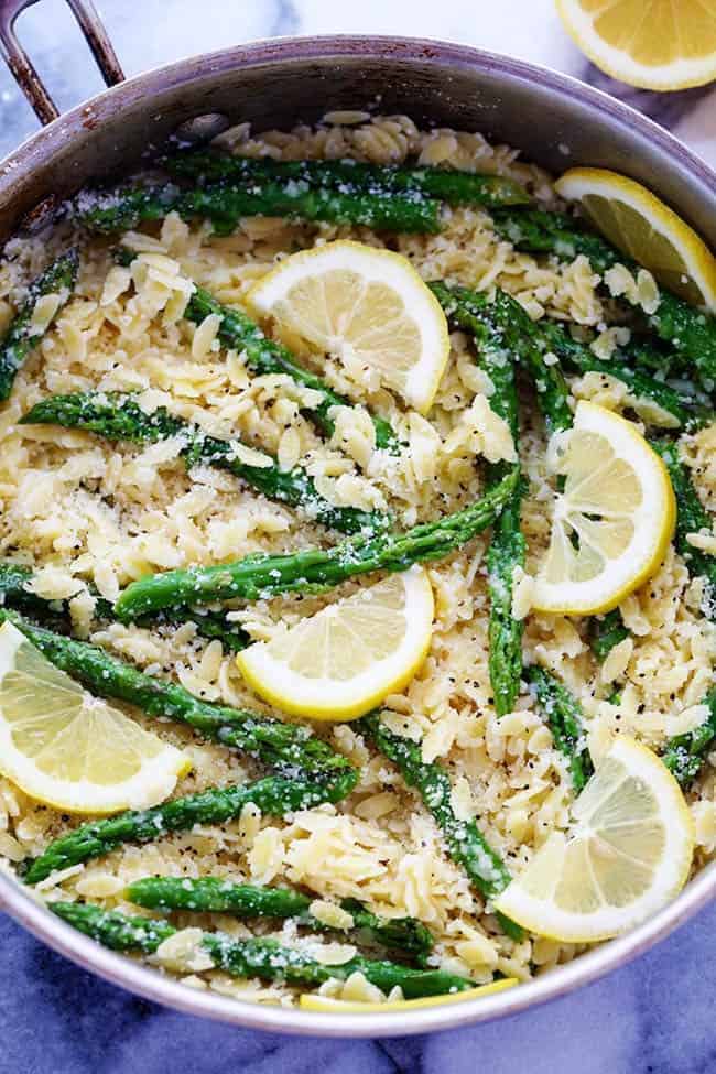 A buttery lemon parmesan garlic sauce coats orzo pasta and gives it such amazing flavor! It gets tossed with asparagus and makes one delicious meal! Lemon Parmesan Garlic Orzo with Asparagus in a metal pot.