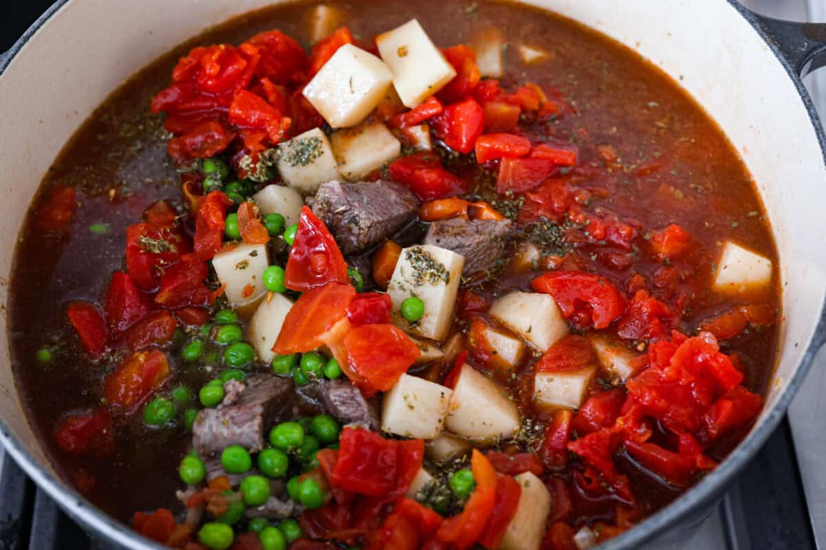 This hearty Vegetable Beef Soup is comforting and flavor-packed! It's loaded with beef, potatoes, and veggies that simmer to tender perfection. A classic and easy one-pot soup for a chilly night. Fourth photo of all the vegetable beef soup ingredients added to the pot to simmer.