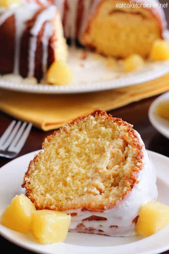Pineapple has such a mild flavor, so it really helps to serve fresh chopped pineapple with this cake to enhance the pineapple flavor. Give it a try or create your own version. . . it will become a new staple recipe in your house. Pineapple Cheesecake Cake on a white plate with pineapple chunks on the side.