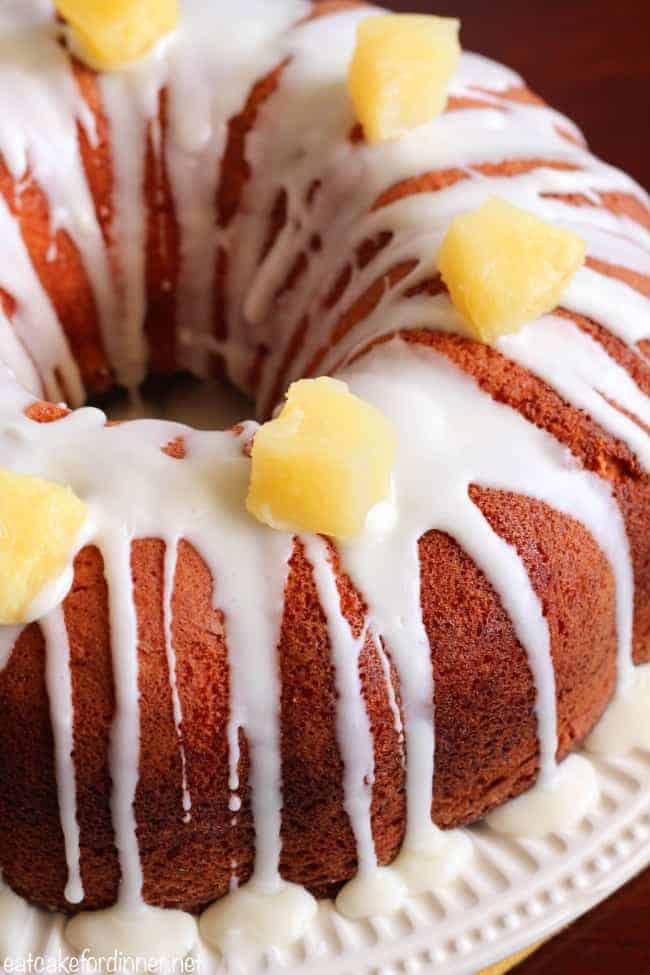 Pineapple has such a mild flavor, so it really helps to serve fresh chopped pineapple with this cake to enhance the pineapple flavor. Give it a try or create your own version. . . it will become a new staple recipe in your house. Pineapple Cheesecake Cake on a cake stand with fresh pineapple chunks on top.
