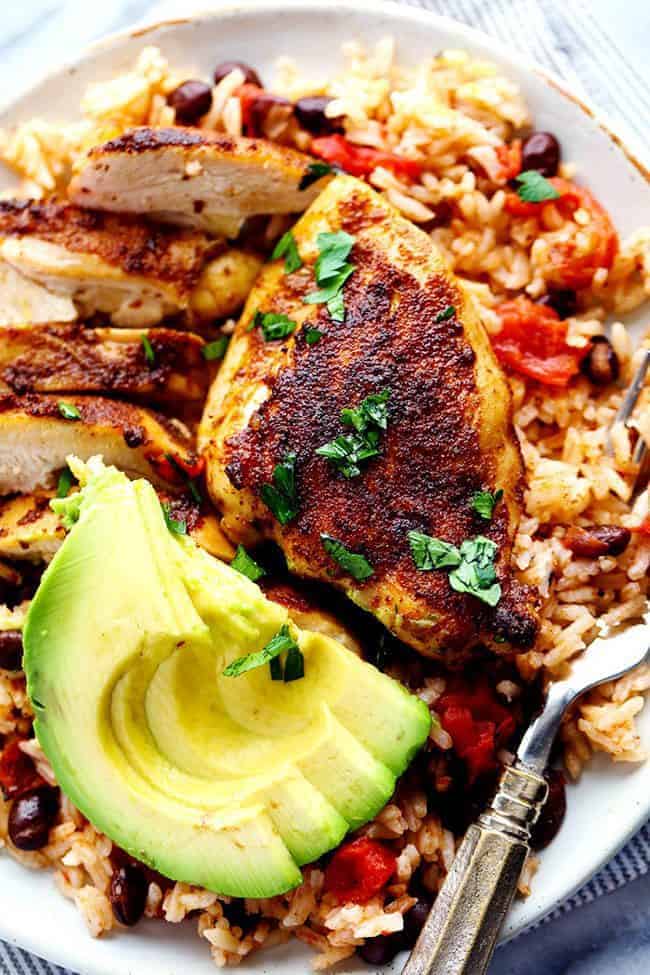 An amazing one pan meal with tender and juicy cajun blackened chicken over delicious southwest rice! This meal became an instant favorite at our house! One Pan Southwest Blackened Cajun Chicken with Rice with fresh cut avocado on a white plate.