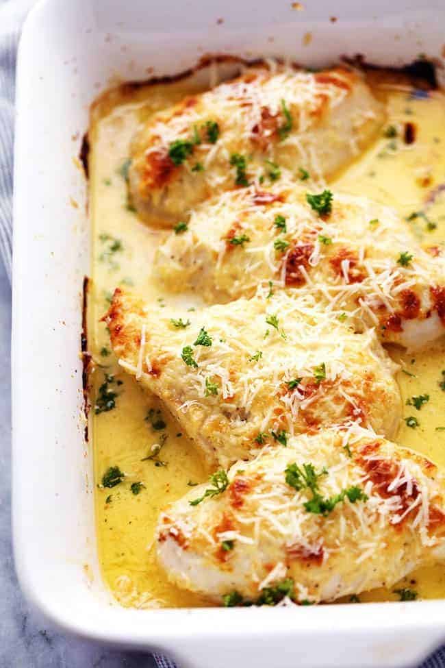 An amazingly creamy baked chicken with asiago cheese inside. It comes together quickly and will be loved by the entire family! Creamy baked asiago chicken in a white casserole dish.