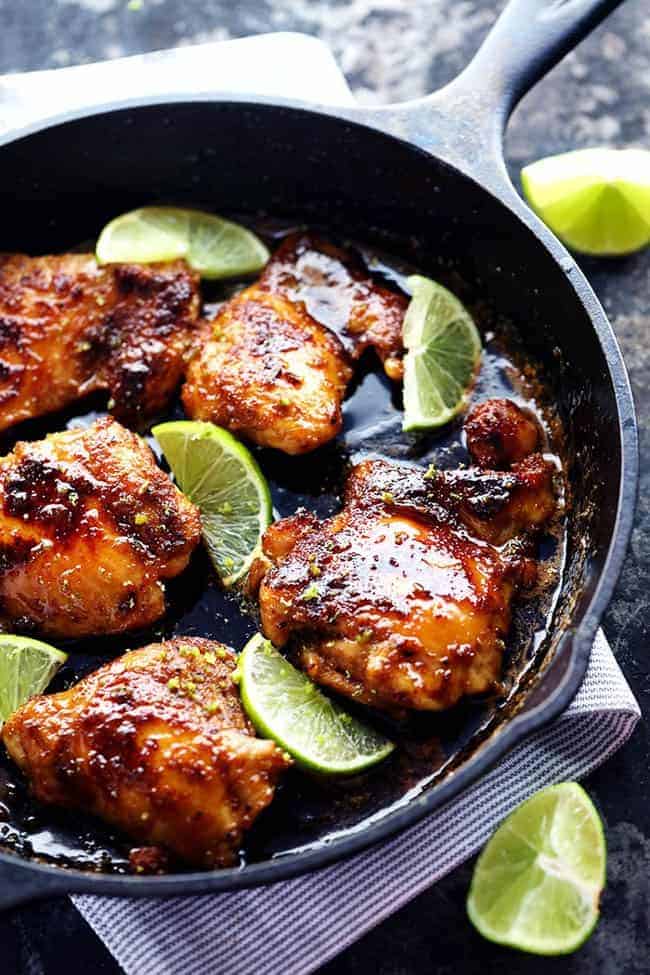 Delicious spiced rubbed chicken cooked to tender and juicy perfection. It gets glazed with the most amazing honey lime sauce and is sure to be a huge hit! Skillet honey lime chicken in a large black skillet. There are freshly cut limes on the side of the skillet.