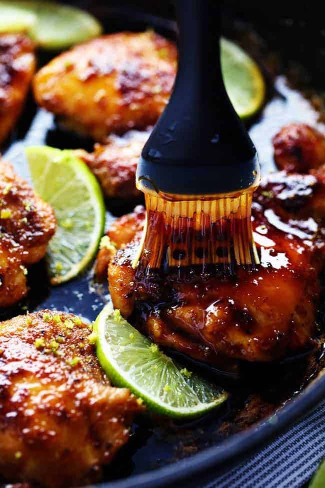 Delicious spiced rubbed chicken cooked to tender and juicy perfection. It gets glazed with the most amazing honey lime sauce and is sure to be a huge hit! Chicken being basted with honey in a skillet.