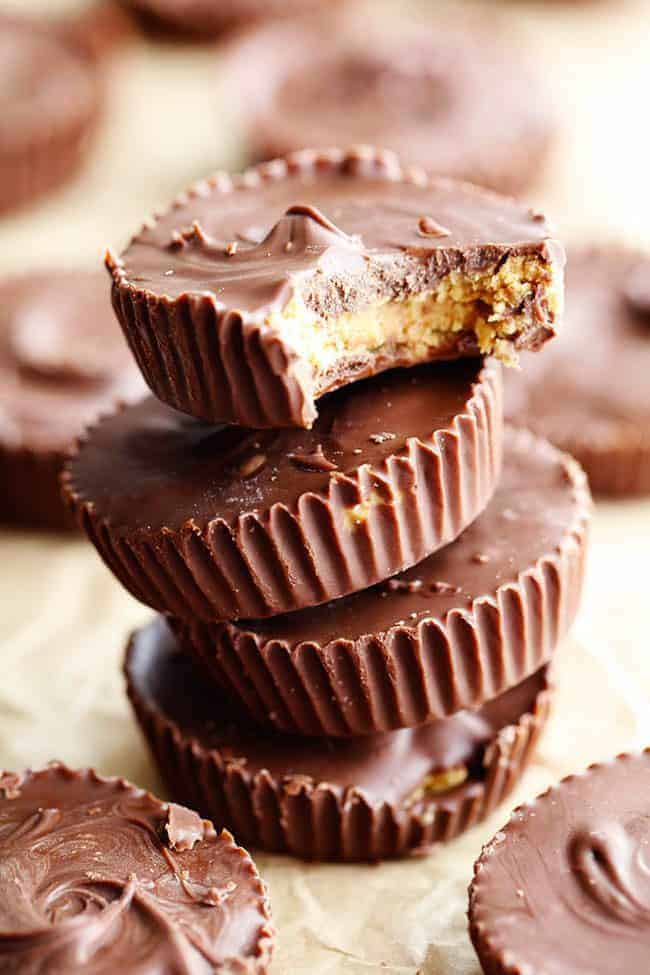 Homemade Reese's Peanut Butter Cupsย come together in just 15 minutes and are even better than the real thing! Homemade Reese's peanut butter cups stacked on top of one another. One with the bite taken out of it.