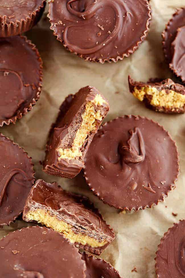 Homemade Reese's Peanut Butter Cupsย come together in just 15 minutes and are even better than the real thing! Homemade Reeses peanut butter cups with some broken in half show the middle.