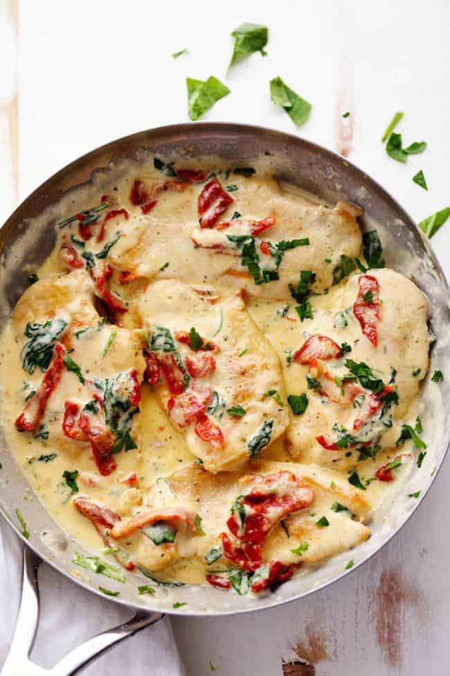Creamy Tuscan Garlic Chicken has the most amazing creamy garlic sauce with spinach and sun dried tomatoes. This is a restaurant quality meal that's easy to make at home in just 30 minutes! Overhead photo of Creamy Tuscan Garlic Chicken in a large frying pan.