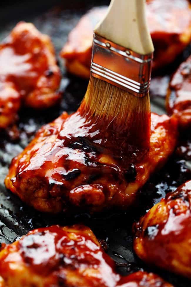 Honey Chipotle BBQ Chicken is sweet and tangy and the chipotle adds such a flavorful kick! You are going to love everything about this sauce and it will be a hit at your next gathering! Basting brush applying honey chipotle sauce to the chicken on the grill.