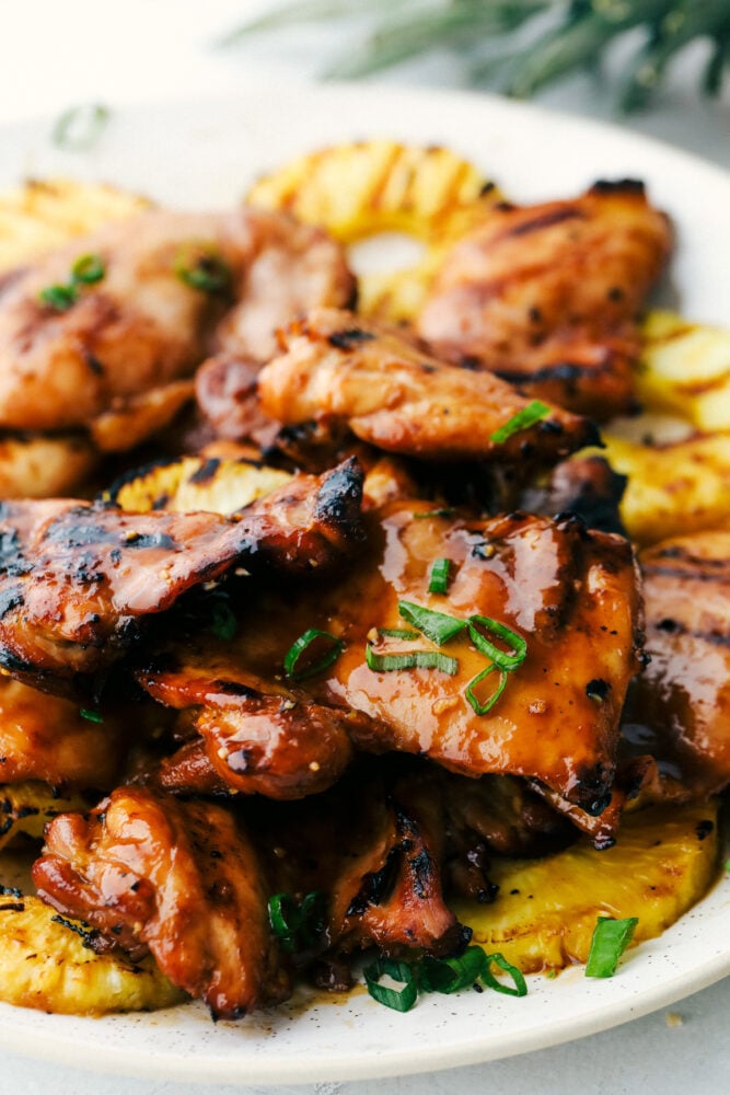 Grilled Huli Huli Chicken is a five star recipe! The marinade is quick and easy and full of such amazing flavor! You will make this again and again! Grilled Huli Huli chicken and pineapple on a plate.