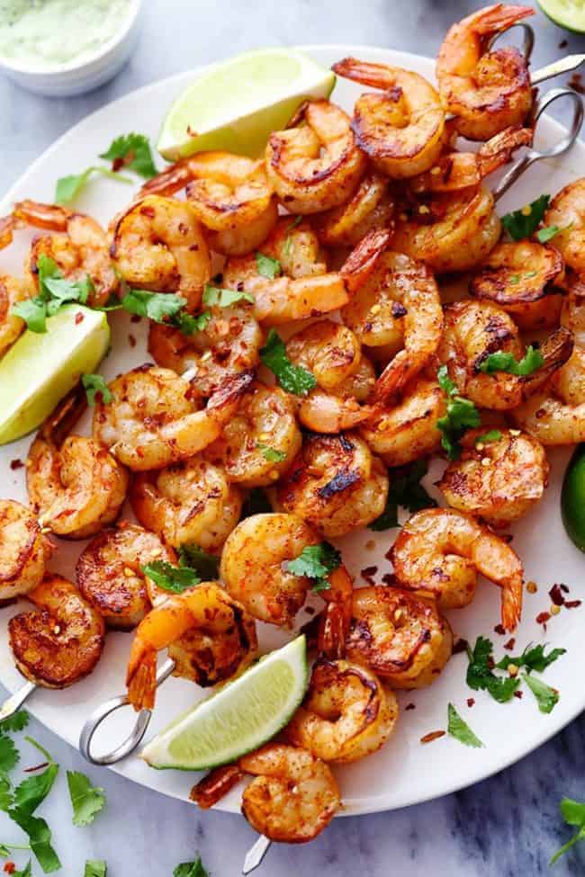 Grilled Spicy Lime Shrimp with Creamy Avocado Cilantro Sauce has a simple but full of flavor and spice marinade. The creamy avocado cilantro sauce is the perfect cool and creamy dipping sauce. Grilled Spicy Lime Shrimp on a white plater.