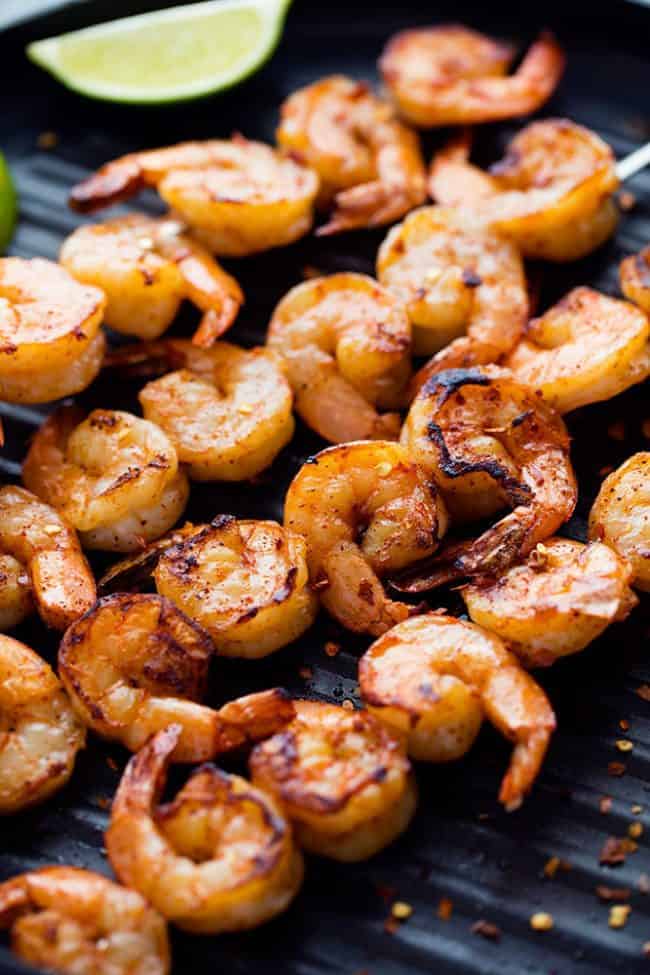 Grilled Spicy Lime Shrimp with Creamy Avocado Cilantro Sauce has a simple but full of flavor and spice marinade. The creamy avocado cilantro sauce is the perfect cool and creamy dipping sauce. Grilled Spicy Lime Shrimp on a grill.