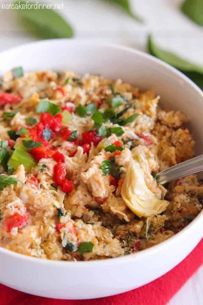 A delicious and healthy meal full of quinoa,ย red pepper, artichokes, spinach, chicken and Greek yogurt. It has such amazing flavors and is a delicious dinner idea! Creamy Spinach and Artichoke Chicken Quinoa in a white bowl with a metal fork.