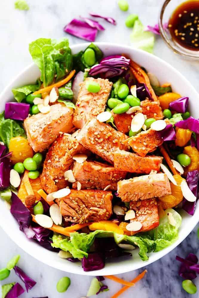 Asian Pan Seared Salmon Salad is bright and vibrant and complete with an amazing honey sesame dressing that takes this salad to a whole new level of delicious! Overhead photo of Asian Pan Seared Salmon Salad in a white bowl.